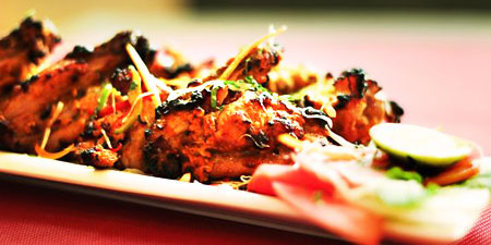 Colourful tandoori chicken with wedges of lemon, carrot, tomato and cabbage in beach restaurant of Bluebay beach resort