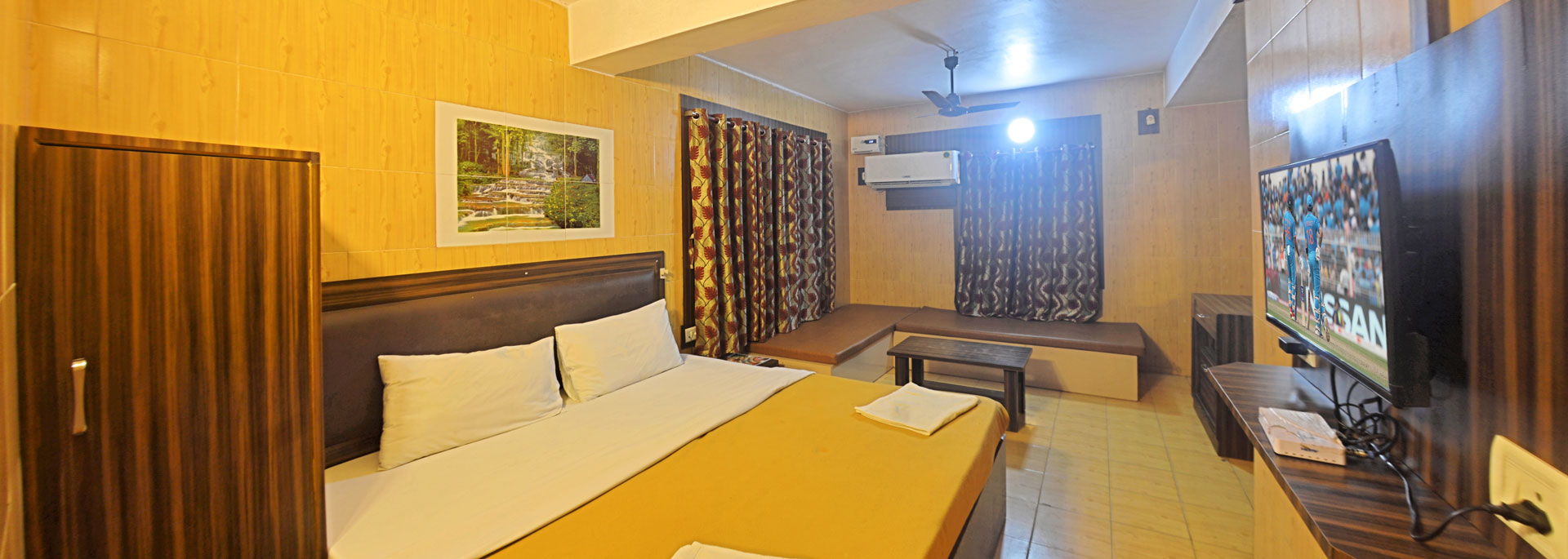 Room with a king size bed, Television, Table, Chairs, fan, dressing table with mirror in Bluebay beach resort