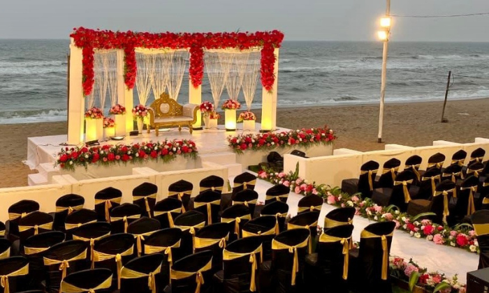 Grand evening wedding reception setup with red floral stage and premium black and gold guest seating by the sea at Blue Bay Resort.